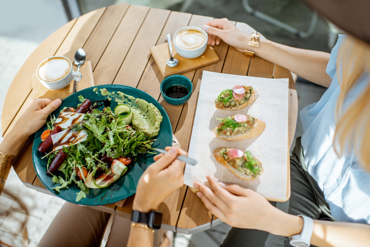 Two people eating healthy food, one a salad and the other bruschetta