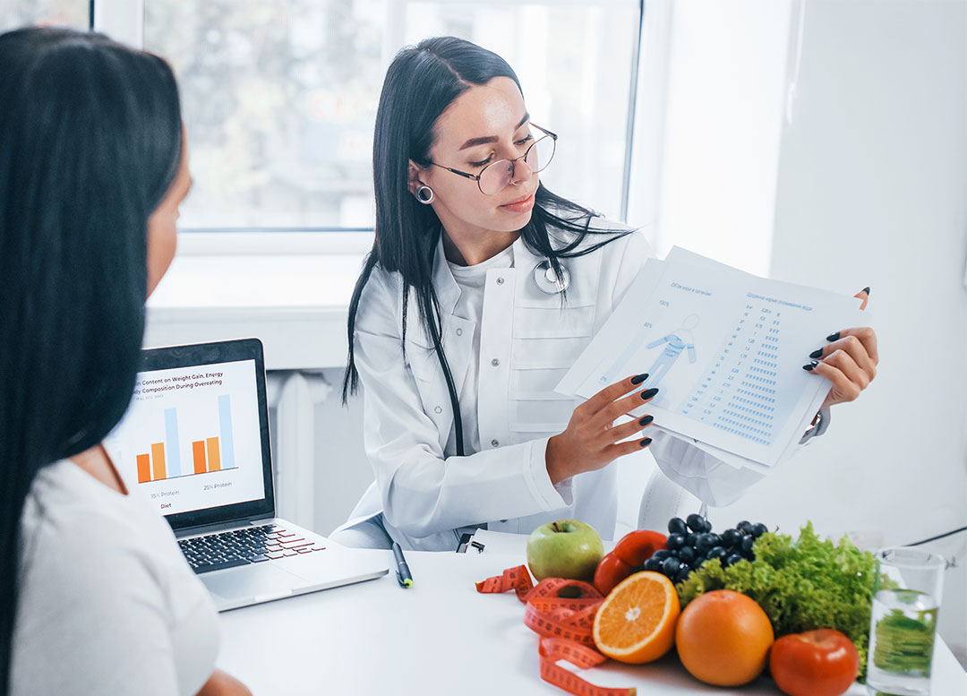 Dietitian explaining information to a client, fruit on table to show healthy choices