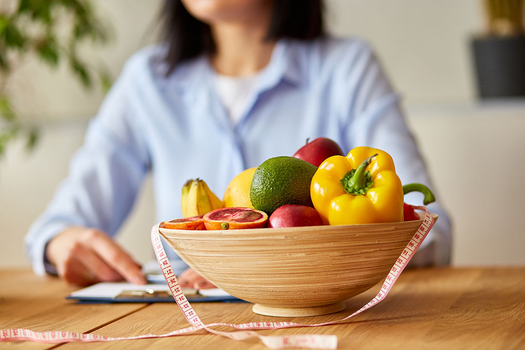 Bowl of fruit and a measuring tape to illustrate a dietitian providing a diet plan