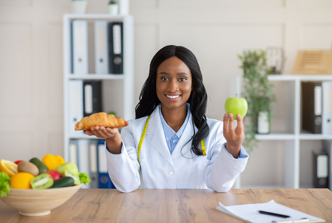 Doctor holding a croissant and an apple to demonstrate healthy choices